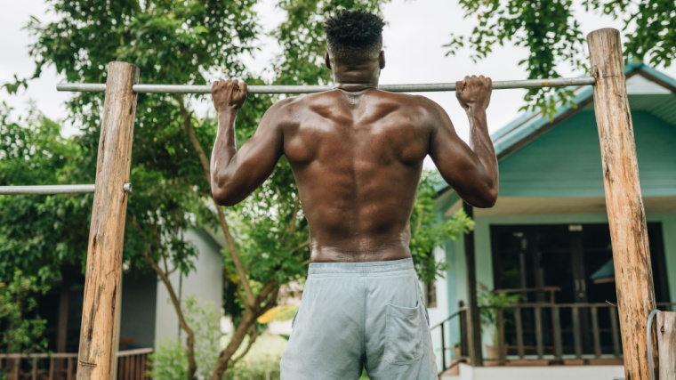 muscular person outdoors doing pull-ups